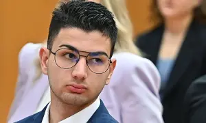 Alex Cotoia, con occhiali e abito blu, ascolta attentamente in tribunale.