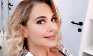 Barbara D'Urso sorride con capelli biondi mossi e trucco accentuato.