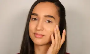 Donna applica fondotinta per definire la mascella, creando un look impeccabile.