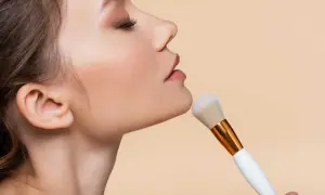 Donna applica cipria con un pennello morbido, un gesto elegante per un look impeccabile.