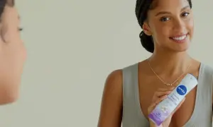 Donna sorridente con spray Nivea Fresh Sensation, un modo per non sudare e sentirsi freschi tutto il giorno.
