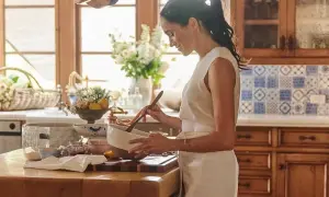 Meghan, Duchessa di Sussex, sorride mentre mescola in una ciotola in una cucina luminosa.