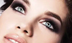 Occhi azzurri con un intenso trucco smokey eyes, labbra lucide e pelle luminosa.