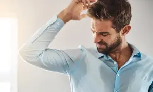 Uomo con camicia bagnata di sudore, preoccupato per le cause del sudore acido.