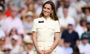 Kate Middleton sorride a Wimbledon, un'icona di stile in un abito chiaro, mentre il pubblico fa da sfondo sfocato.
