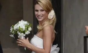Michelle Hunziker sorride con un bouquet, indossando un abito da sposa che ricorda quello del suo matrimonio con Eros Ramazzotti.