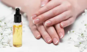 Olio per unghie e cuticole secche, con mani curate e fiori bianchi.