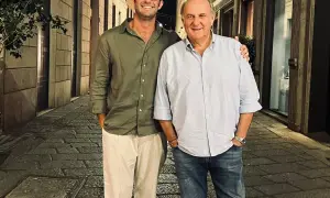 Edoardo Scotti sorride con un amico in una strada acciottolata di sera.