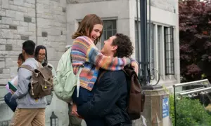 Un ragazzo solleva la sua fidanzata, entrambi sorridono felici davanti a un edificio. Belmont Cameli e la sua fidanzata in un momento di gioia.