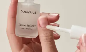 Mani curate con unghie lunghe e sane, applicando un prodotto per ammorbidire le cuticole.