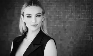 Ritratto in bianco e nero di una donna con capelli biondi, indossa un abito nero e una collana. Sembra la donna più bella del mondo.