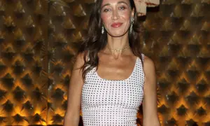 Alana Hadid indossa un abito bianco tempestato di cristalli, con un choker scintillante e orecchini pendenti.