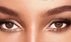 Occhi marroni esaltati da un trucco scintillante color bronzo, ciglia lunghe e folte, sopracciglia definite.