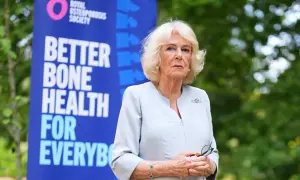 Camilla, regina consorte del Regno Unito, sorride con un banner della Royal Osteoporosis Society alle spalle.
