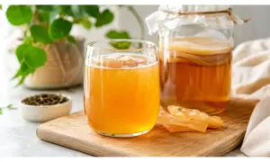 Bicchiere di kombucha frizzante accanto a un barattolo fermentato. Attenzione alle controindicazioni del kombucha per alcuni soggetti.