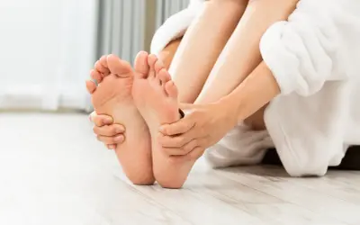 Mani che massaggiano delicatamente i piedi, mostrando come massaggiare i piedi per alleviare la tensione e favorire il benessere.