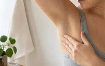 Mano che sfiora l'ascella, un gesto che ci ricorda perchè il sudore puzza e come prendersene cura.