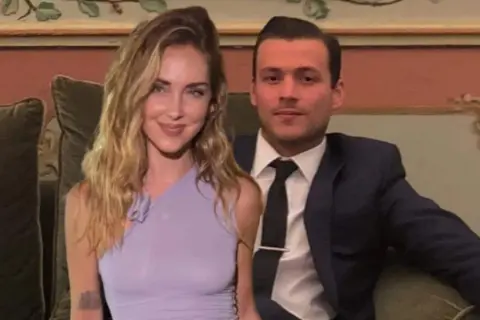 Chiara Ferragni e il suo fidanzato Fedez, sorridenti, seduti su un divano in un ambiente elegante.