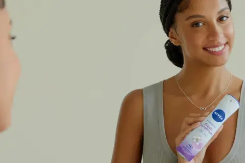 Donna sorridente con spray Nivea Fresh Sensation, un modo per non sudare e sentirsi freschi tutto il giorno.