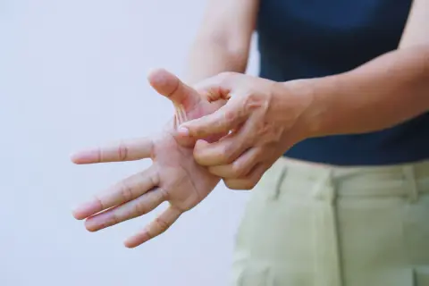 Mano che si gratta il palmo, un gesto che indica un forte prurito alle braccia.