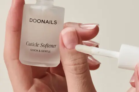 Mani curate con unghie lunghe e sane, applicando un prodotto per ammorbidire le cuticole.