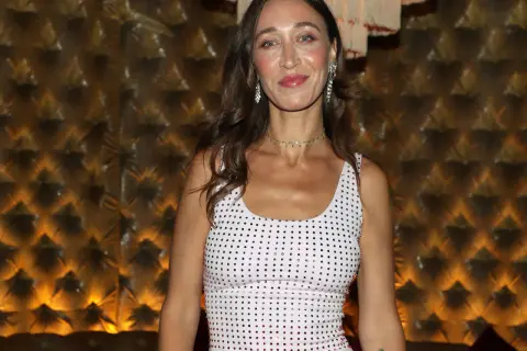 Alana Hadid indossa un abito bianco tempestato di cristalli, con un choker scintillante e orecchini pendenti.