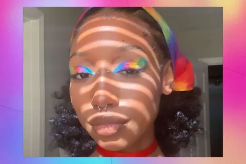 Make up pride: un volto con un trucco arcobaleno sugli occhi e una fascia colorata.