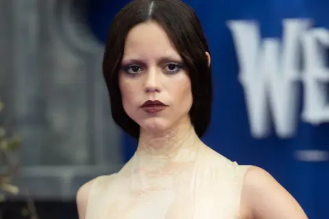 Donna con trucco Halloween semplice: occhi scuri, labbra bordeaux e pelle effetto squame.