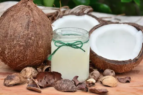 Un barattolo di olio di cocco, circondato da noci di cocco e gusci, pronto a rivelare i suoi benefici.