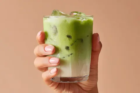Mano con un bicchiere di matcha ghiacciato. Attenzione alle matcha controindicazioni per goderselo al meglio.
