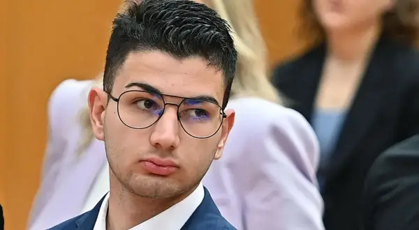 Alex Cotoia, con occhiali e abito blu, ascolta attentamente in tribunale.