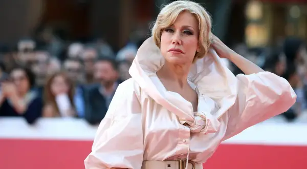 Nancy Brilli con un abito bianco voluminoso e una cintura con fibbia a B, posa sul red carpet.