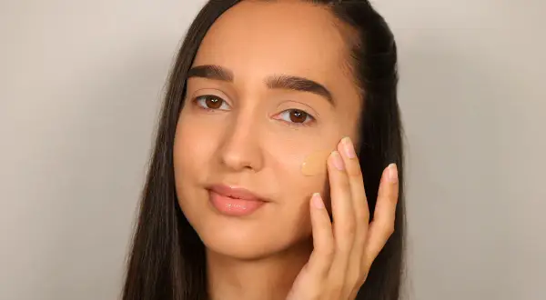 Donna applica fondotinta per definire la mascella, creando un look impeccabile.