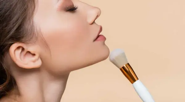 Donna applica cipria con un pennello morbido, un gesto elegante per un look impeccabile.