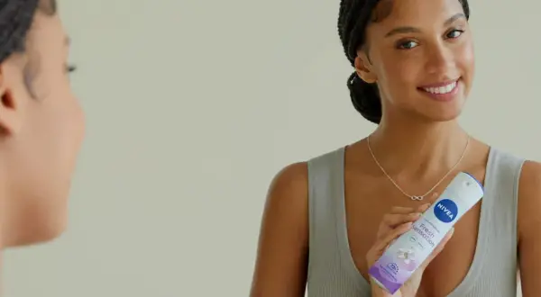 Donna sorridente con spray Nivea Fresh Sensation, un modo per non sudare e sentirsi freschi tutto il giorno.