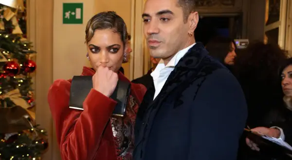 Elodie e Marracash, una coppia elegante, posano vicino a un albero di Natale addobbato.