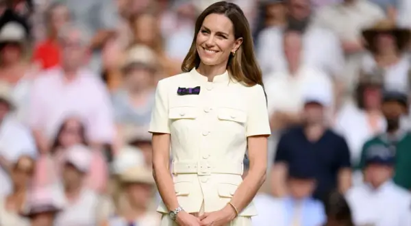 Kate Middleton sorride a Wimbledon, un'icona di stile in un abito chiaro, mentre il pubblico fa da sfondo sfocato.
