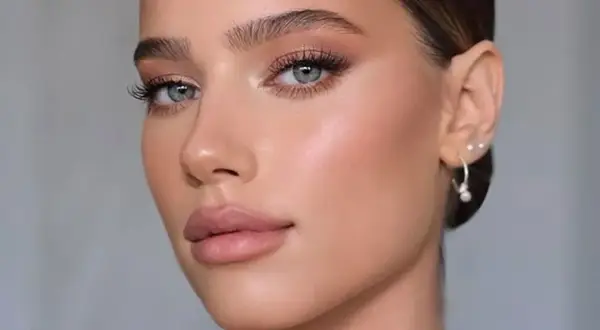 Viso di donna con un trucco giorno naturale, labbra morbide e occhi luminosi.