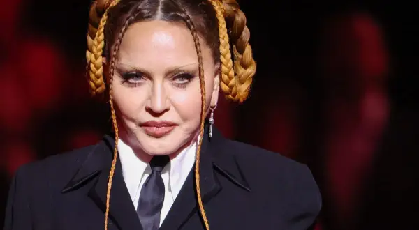 Madonna con trecce bionde e abito scuro, un look iconico per il suo compleanno.