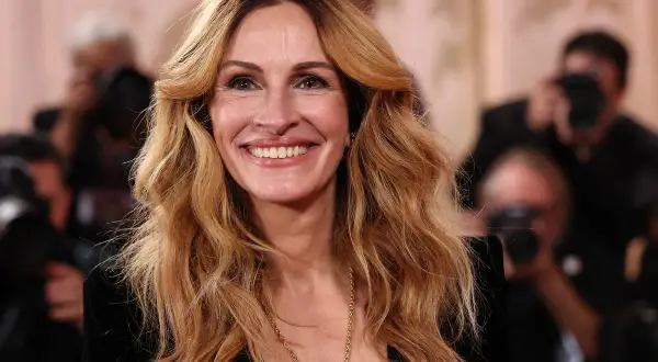 Julia Roberts oggi, sorridente e radiosa, con i suoi iconici capelli biondi mossi e una collana dorata.
