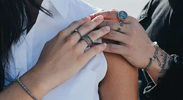Mani con anelli che esplorano il significato anelli dita. Un bracciale e un anello con bussola completano il look.