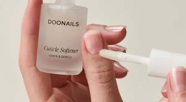 Mani curate con unghie lunghe e sane, applicando un prodotto per ammorbidire le cuticole.