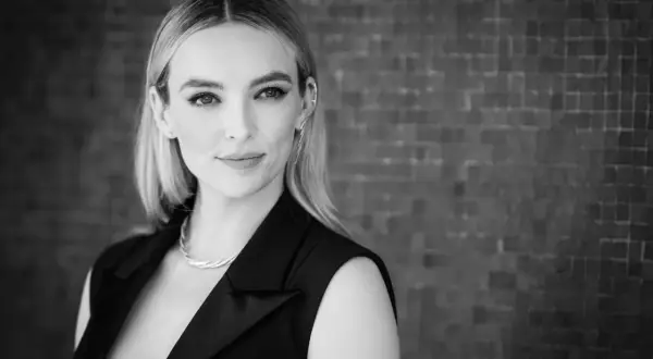 Ritratto in bianco e nero di una donna con capelli biondi, indossa un abito nero e una collana. Sembra la donna più bella del mondo.