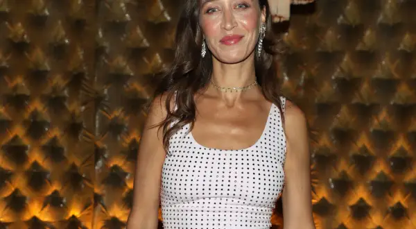 Alana Hadid indossa un abito bianco tempestato di cristalli, con un choker scintillante e orecchini pendenti.