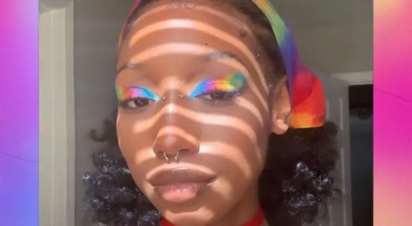 Make up pride: un volto con un trucco arcobaleno sugli occhi e una fascia colorata.
