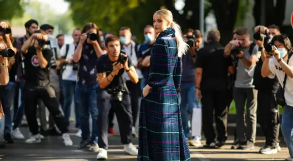 Modella con abito lungo a fantasia, circondata da fotografi. Un'anteprima della fashion week milano 2026.