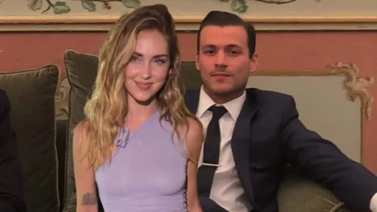 Chiara Ferragni e il suo fidanzato Fedez, sorridenti, seduti su un divano in un ambiente elegante.