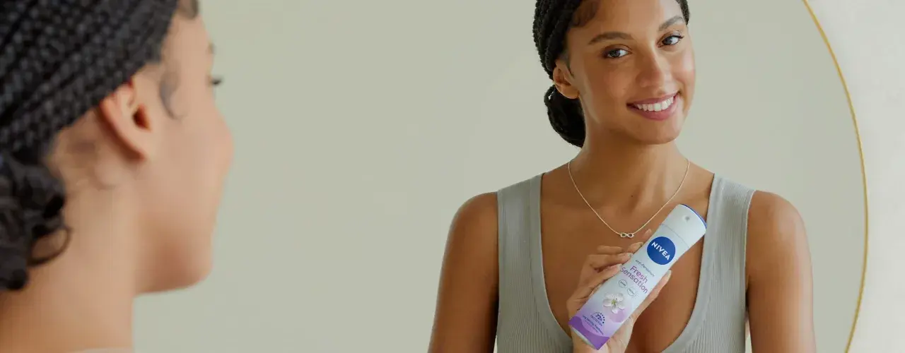 Donna sorridente con spray Nivea Fresh Sensation, un modo per non sudare e sentirsi freschi tutto il giorno.