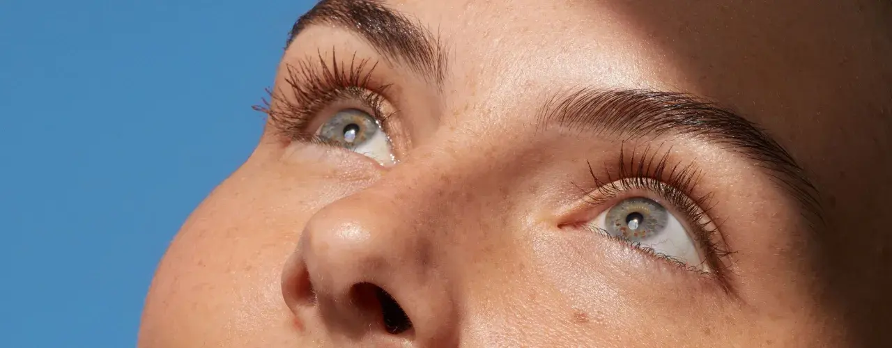 Occhi con ciglia lunghe e folte, pelle luminosa con lentiggini. Scopri come struccarsi senza struccante per un viso fresco e naturale.