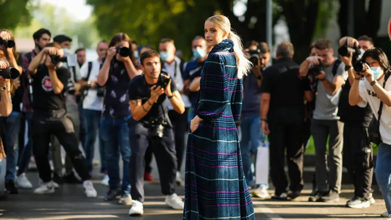 Modella con abito lungo a fantasia, circondata da fotografi. Un'anteprima della fashion week milano 2026.